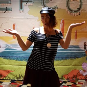 Photo of me in a leather hat with a side-pulled hairdo standing in front of a colourful sign that reads: DEFCON